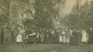 Anhöriga och vänner tar avsked av den avlidne. Okända personer och fotograf. En bild tagen mellan 1910-1929. Anhöriga och vänner tar avsked av den avlidne på gården innan kistans lock sätts på.