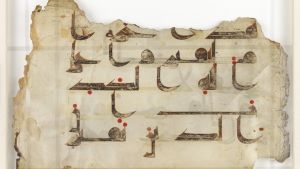 Detail of page showing fragment of Qur'an text. Written in blackish brown ink on vellum, these fragments of the Qur'an have a variety of origins and chart the change from the angular Kufic to more cursive Naskhi variation of the Arabic alphabet. Although
