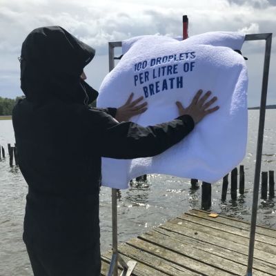 person i svart med tygplansch på brygga