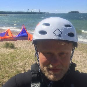 Niko Karstikko är sommarhangöbo sedan 90-talet. Niko Karstikko i våtdräkt med en vit hjälm på huvudet på en strand i Hangö.