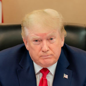 Donald Trump sa att det inte finns rum för våld och vandalism inom hans rörelse. Donald Trump seuraa videoneuvottelua G20 kokouksessa. Taustalla USA:m ja USA:n presidentin liput.