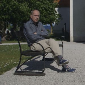 Jörn Donner sitter på en bänk utanför kyrkan på Fårö.