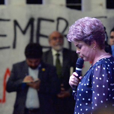 Seinässä teksti Temer, etualalla mikrofoniin puhuva Dilma Rousseff.