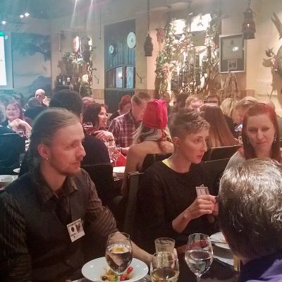 Pikkujoulun juhlijoita ravintolasalissa, taustalla Twitter-seinä