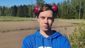 Jeff Sjöberg ska börja jobba vid familjens lantbruk i juni. Jeff Sjöberg, en man ljushårig man i blå collegetröja står med armarna i kors framför en åker.