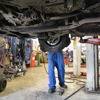 Työntekijä korjaa autoa.