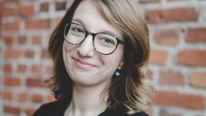 Maija Pelli sjunger i Pedavoces som börjat med fysiska övningar igen efter en vår av distansövningar. Maija Pelli står i svart blus framför brun tegelvägg.