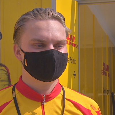 Roope Saarikivi, en man med svart munskydd och gulröd skjorta, arbetar som cykelbud.