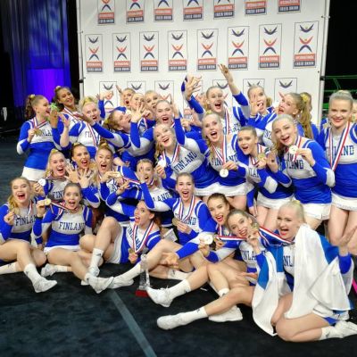 Suomen naisten cheerleadingin maajoukkue tuulettaa ryhmäkuvassa.