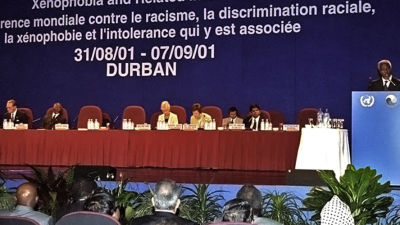 Kofi Annan håller ett tal bredvid en panel.