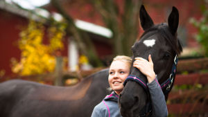 Vaalea nainen halaa hevosen päätä