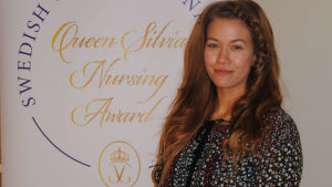 Maiju Björkqvist. Maiju Björkqvist bredvid en skylt var det står Queen Silvia Nursing Award.