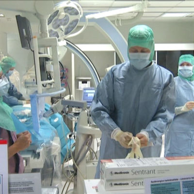 Kirurg drar på sig skyddsutrustning i en operationssal.