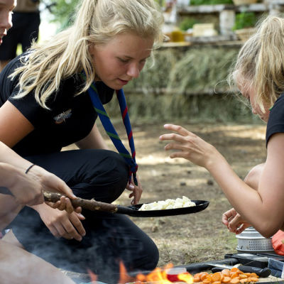 scoutflickor lagar mat över öppen eld