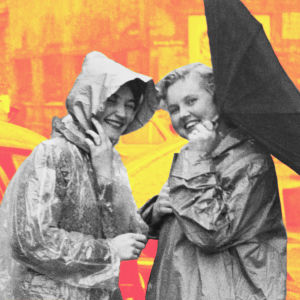 Kaksi naista sateenvarjo nurin poseeraavat sadetakeissa kameralle matkalla Hampurissa.