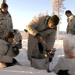Varusmiehet ruokailevat talvisessa metsässä.
