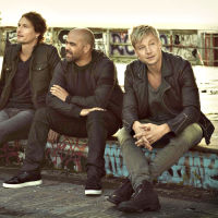 Fyra män klädda i mörka färger och läderrockar sitter i en urban miljö tillsammans.