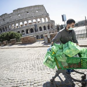 Mies työntää ostoskärryjä autiolla turistialueella Roomassa.