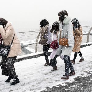 Turistit kävelevät lumimyrskyssä Lontoossa