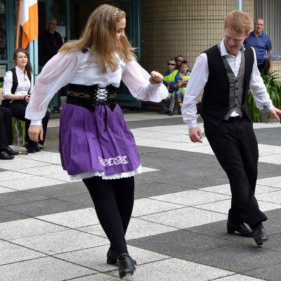 Irlantilaisen kansantanssiryhmän kaksi jäsentä esiintyy kirjaston pihassa, taustalla soittajia