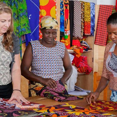 Katja Kokkoniemi ja kaksi namibialaisnaista afrikkalaisten kankaiden äärellä
