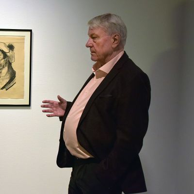 Mies tutkii litografia, joka on ripustettu taidemuseon seinälle