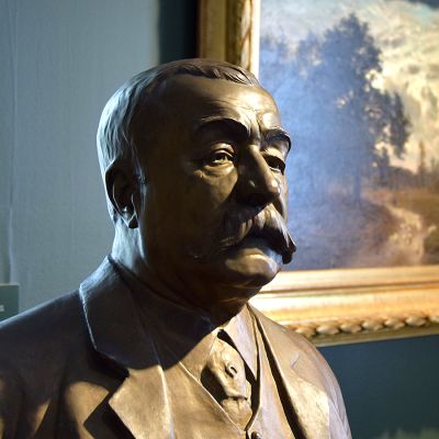 Rintakuva taiteilijasta, jonka teos näkyy taustalla