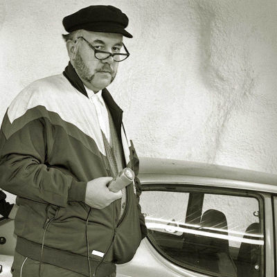Cafe Veijon baarin toimittaja Jukka Lindfors mikrofoni kädessään Datsun 100A:n vierellä.