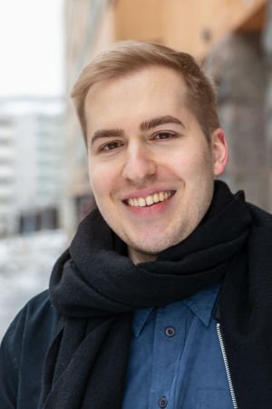 Hermanni Hyyryläinen on 27-vuotias videobloggaaja Hermanni Hyyryläinen seisoo hymyilevänä ulkona kadulla kerrostalon edessä.
