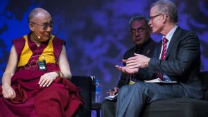 Charlie Scudamore (längst till höger) här tillsammans med Dalai Lama under en konferens i Sydney om glädjens betydelse. två män sitter och diskuterar