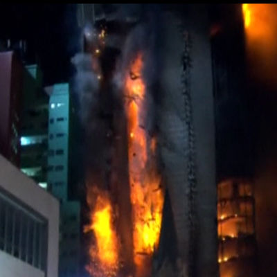 Brinnande våningshus rasar ihop.