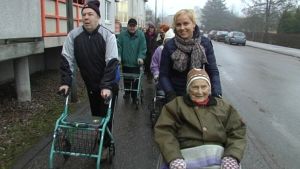 Laura Sormunen (bakom rullstolen) på promenad med äldre Borgåbor. Många äldre på promenad med Laura Sormunen i spetsen som skuffar på Doris Sten.