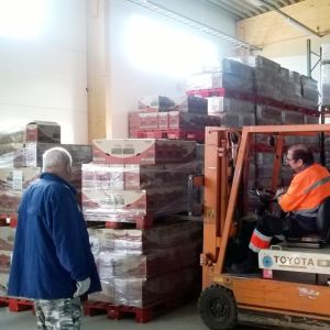 Tiotals volontärer jobbar med verksamheten i Mäntsälä. En truck flyttar varor i en lagerhall. En man i förarhytten, en annan tittar på.