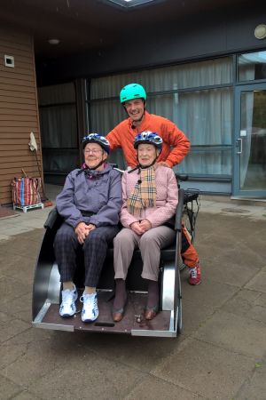 Margit Antell (till vänster) och Aldi Waxlax får ta en tur med Jonathan Granbacka. jonathan granbacka sitter som cykelpilot på en cykelriksha och skjutsar åldringarna aldi waxlax och margit antell