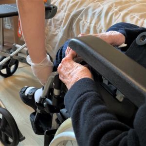 Hoitaja auttaa hoivakodin asukasta pyörätuolin kanssa. 
