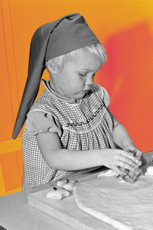 Kuvassa on kaksi lasta tonttulakit päässä leipomassa vuonna 1958