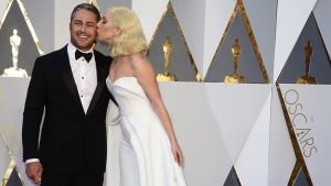 Lady Gaga antaa suukon kihlatulleen Taylor Kinneylle Oscar-gaalan punaisella matolla. // Kuva: EPA/Mike Nelson