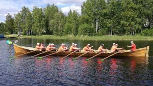 Roddmarthorna har en manlig styrman. Resten av laget består av kvinnor. Kyrkbåt med roddare.
