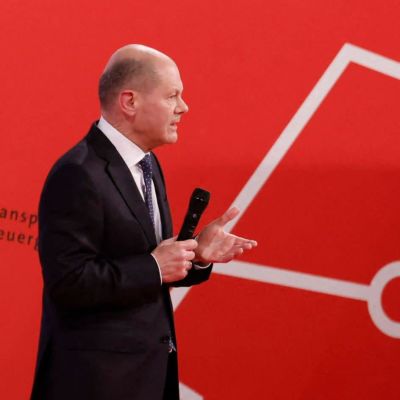 Olaf scholz står på ett podium - i bakgrunden syns stora bokstäver i rött som bokstaverar SPD