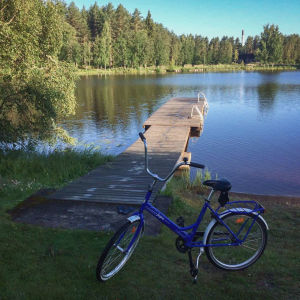 Aamu-uinti jätti jalanjäljet laiturille. Sininen polkupyörä rannalla, taustalla laituri ja vettä