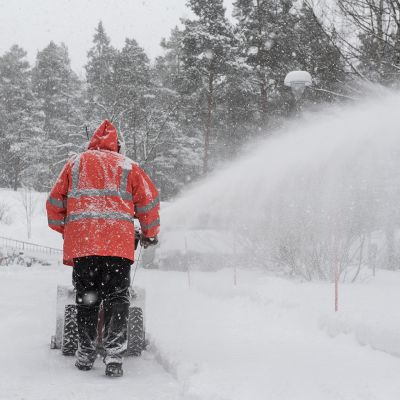 Mies työntää lumilinkoa.