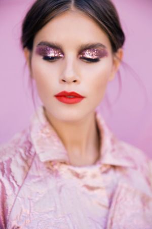 Glitter på ögonlocken och i sidenkimonon i Katri Niskanens nya look. En modern Madama Butterfly. En kvinna med slutna ögon i en rosa glittrig kimono.