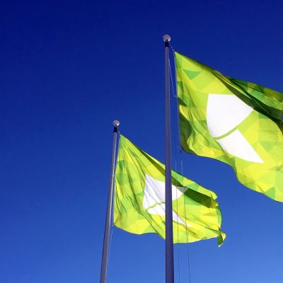 Karelia-ammattikorkeakoulun liput liehuvat sinistä taivasta vasten Joensuussa.