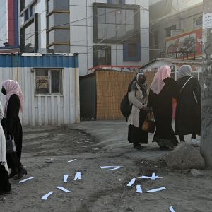 Afganistanilaisia naisia pienissä ryhmissä kadulla yliopistorakennuksen edessä.