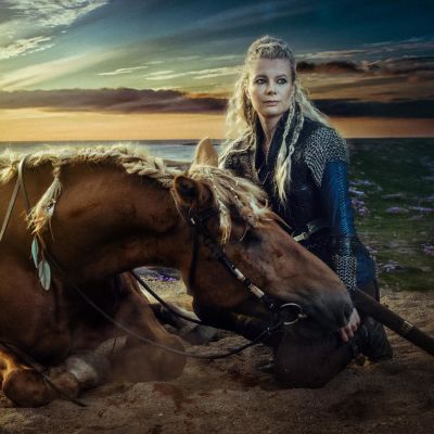 Nainen istuu hevosen vierellä rannalla auringonlaskussa. Valokuvaaja Antti Karppisen valokuva, joka jäljittelee Vikings televisiosarjan fantasiatyyliä.
