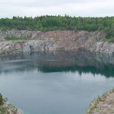 En sjö syns mitt på bilden med kalkstensberg runt omkring och skog i bakgrunden. Svartå kalkstensbrott.