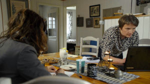 Varje asylfall inebär stora textmängder Två kvinnor vid ett matbord. Den ena tittar på en laptop.