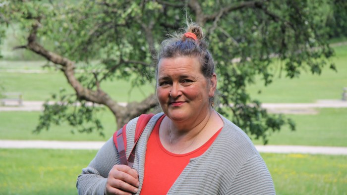 psykologi Liisa-Uusitalo seisoo puistossa takana kaunis puu katsoo lempeästi kameraan