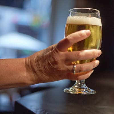 A glas of beer in a women's hand.