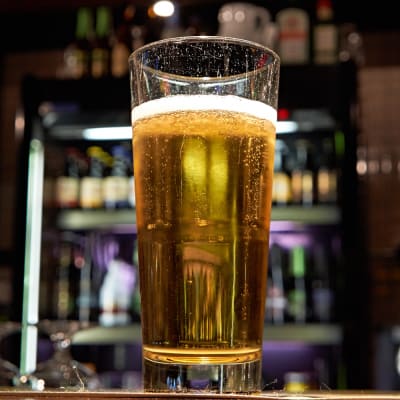 A glass of beer on a bar.